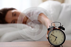 Sleepy young woman stretching hand to ringing alarm willing turn it off. Early wake up, not getting enough sleep