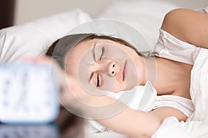 Sleepy young woman turns off signal of alarm clock