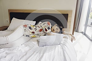 A sleepy young woman yawning while working from the bed