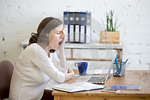 Sleepy young worker woman yawning