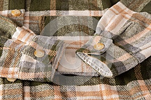 The sleeves and cuffs of the shirt are plaid. Clothing background large. Beige buttons. Unisex plaid shirt. Cuff on