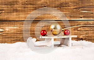 Sleigh with christmas balls on a wooden background