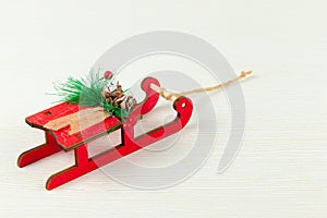 Sleigh of santa claus with fir-tree cones and green spruce branches against a background of white wood with gold veins