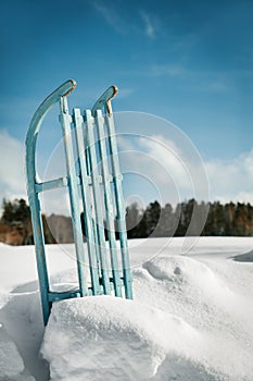 Sleigh or sledge standing in the snow, blue sky in the background, concept winter season