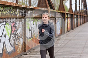 Slender athletic woman jogging on a bridge