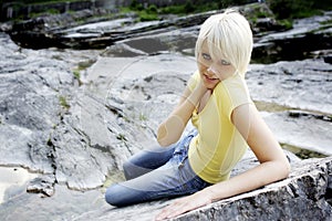Slender beautiful young woman relaxing on a rock