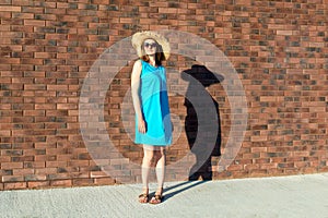 Slender Caucasian woman in blue dress and straw hat with fatty shadow on the wall. The concept of inadequate perception of one`s