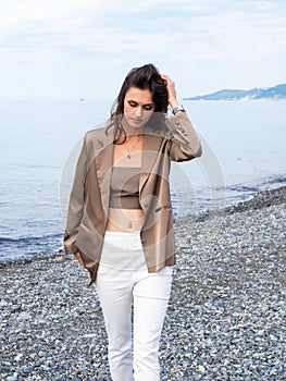 slender fashion model walks along the seashore. Beautiful young tall woman on the beach