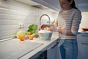 Slender female on diet cooking quick fresh healthy salad by drying greenery in hand food centrifuge.