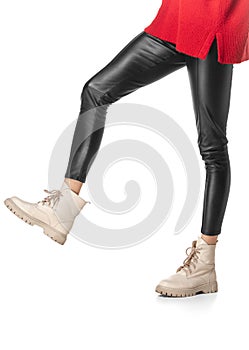 Slender female legs in black leggings and boots isolated on white background