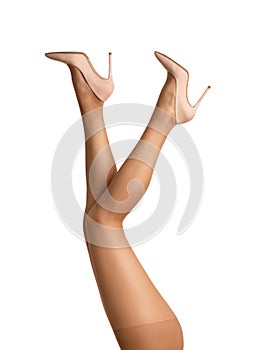 Close-up of slender legs of a girl in tights and high-heeled shoes raised up isolated on a white background
