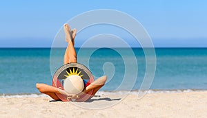 A slender girl on the beach in a straw hat in the colors of the Antigua and Barbuda flag.