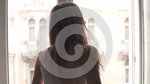 Slender girl cleaning window with rag while doing housekeep work at home