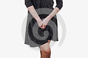 Slender girl in a dark dress experiences discomfort in the uterus, pain, hands between her legs. Incontinence, need to pee in the