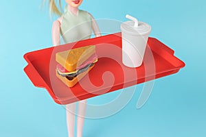 A slender girl with a drink and a sandwich on a tray