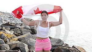 Slender girl with the flag of Canada on the seashore on a sunny summer day