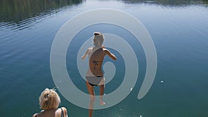 Slender girl jumping into lake water