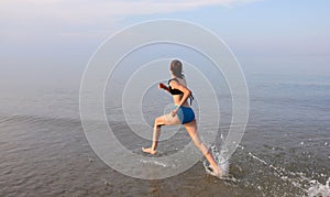 slender girl running with very wide strides on the sea shore photo