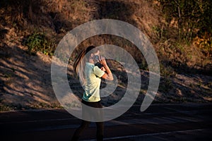 Slender girl in sportswear is jogging, holding smartphone in hands. Business woman talking on phone