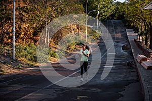 Slender girl in sportswear is jogging, holding smartphone in hands. Business woman talking on phone