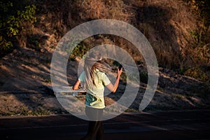 Slender girl in sportswear is jogging, holding smartphone in hands. Business woman talking on phone