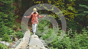 Slender girl walking along a log through a mountain river in the forest. Tourism in the Caucasus Reserve. Goes towards