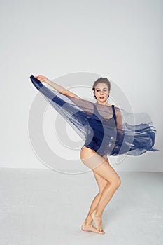 A slender gymnast in black tights dances with a blue chiffon that develops.Aesthetics of dance