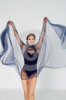 A slender gymnast in black tights dances with a blue chiffon that develops.Aesthetics of dance