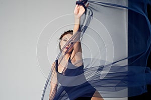 A slender gymnast in black tights dances with a blue chiffon that develops.Aesthetics of dance