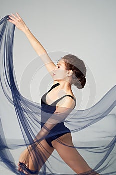 A slender gymnast in black tights dances with a blue chiffon that develops.Aesthetics of dance