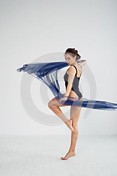 A slender gymnast in black tights dances with a blue chiffon that develops.Aesthetics of dance