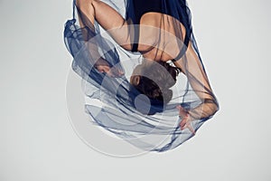 A slender gymnast in black tights dances with a blue chiffon that develops.Aesthetics of dance