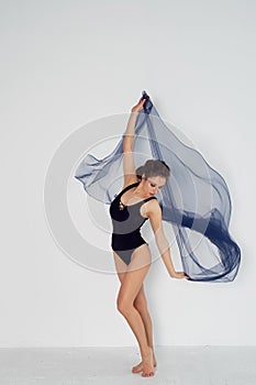 A slender gymnast in black tights dances with a blue chiffon that develops.Aesthetics of dance