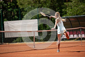 Slender lady is playing tennis on court
