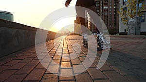 Slender legs of a girl figure skater in roller skates ride on the cobblestones.