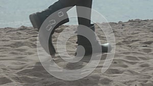 Slender legs of the girl, who was walking on the beach in black shoes