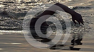 Slender man swims crawl in lake waters at sunset in slo-mo