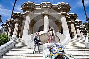 Slender pretty woman with bright curly hair on the white stairs of Park Guell