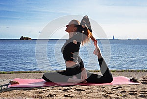 Slender redhead girl is engaged in yoga on the beach