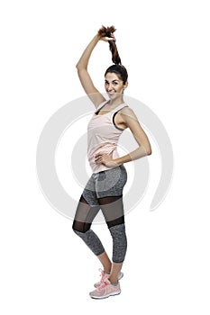 Slender smiling woman in sportswear. A beautiful brunette holds her braid in black leggings and a pink top. Activity, energy and