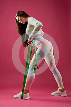 Slender sportswoman with resistance rope, during fitness training.