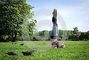 Slender woman doing yoga in the Park on a Sunny day, the girl is lying on her back and lifted her legs up