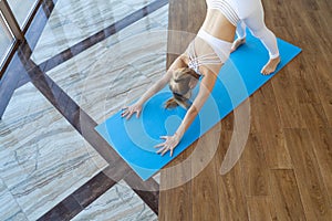 Slender woman in downward dog pose. Girl doing yoga indoors.