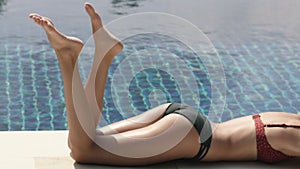 Slender woman legs sunbathes near pool