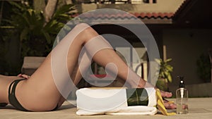 Slender woman legs sunbathes near villa