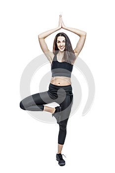 A slender woman in sportswear does exercises. Beautiful brunette in black leggings and top. Health, sports and slimness. Full