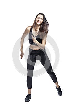 A slender woman in sportswear does exercises. Beautiful brunette in black leggings and top. Health, sports and slimness. Full