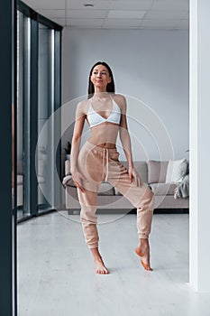 Slender woman in white underwear standing indoors in room at daytime