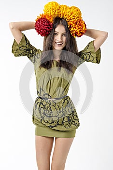 Slender young brunette woman in a dress with a bouquet of autumn flowers on her head