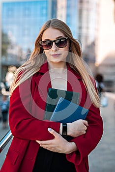 slender young lady in a classic jacket with chic hair is smiling in the middle of the city.